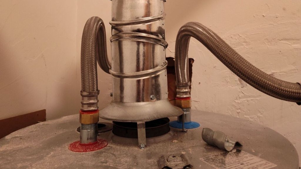 a metal water heater with a hose attached to it