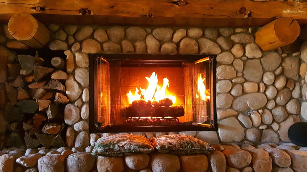 a fireplace with logs and a chair in front of it