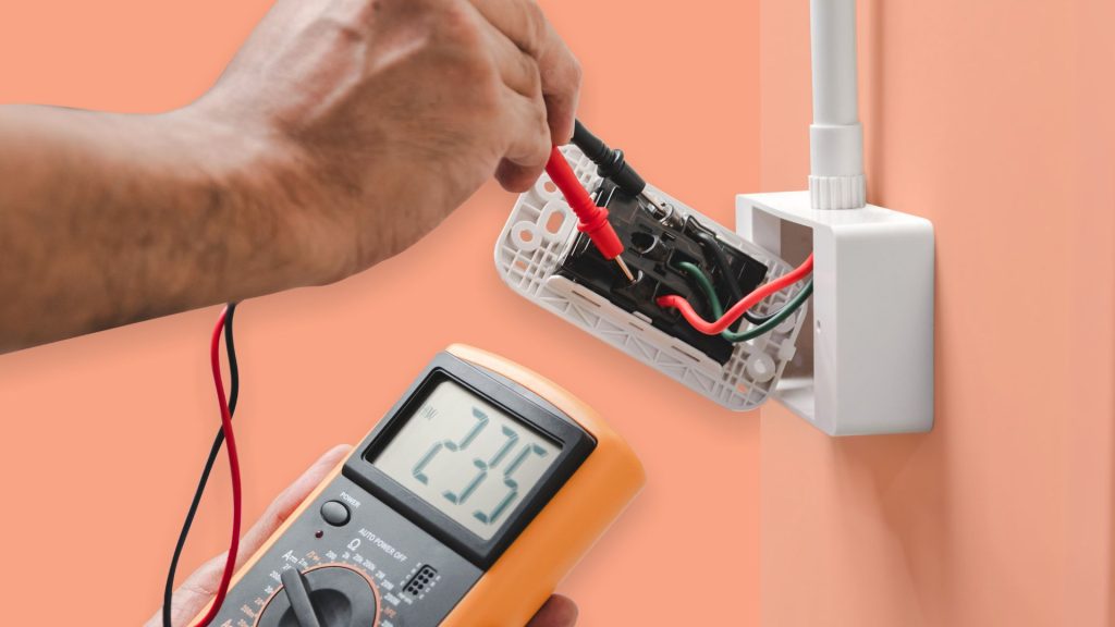 a person using a multimeter to check an electrical outlet