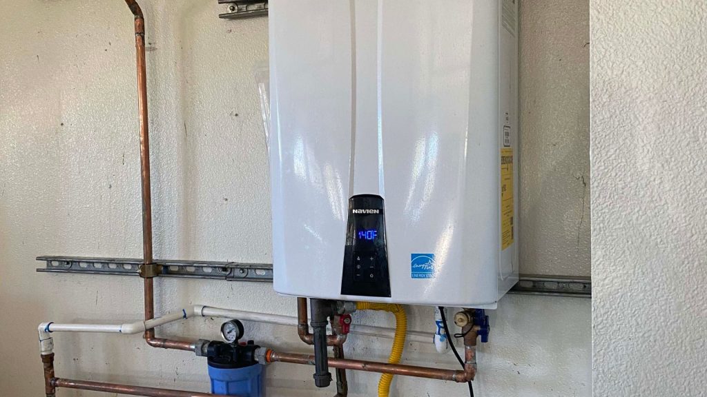 a tankless water heater on a wall next to pipes