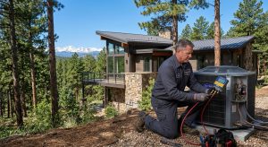 An HVAC technician uses a digital gauge to service an outdoor air conditioning unit at a mountain residence